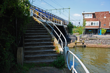 900112 Gezicht op de trapopgang voor het voetpad langs de spoorbrug over de Vaartsche Rijn te Utrecht, met rechts het ...
